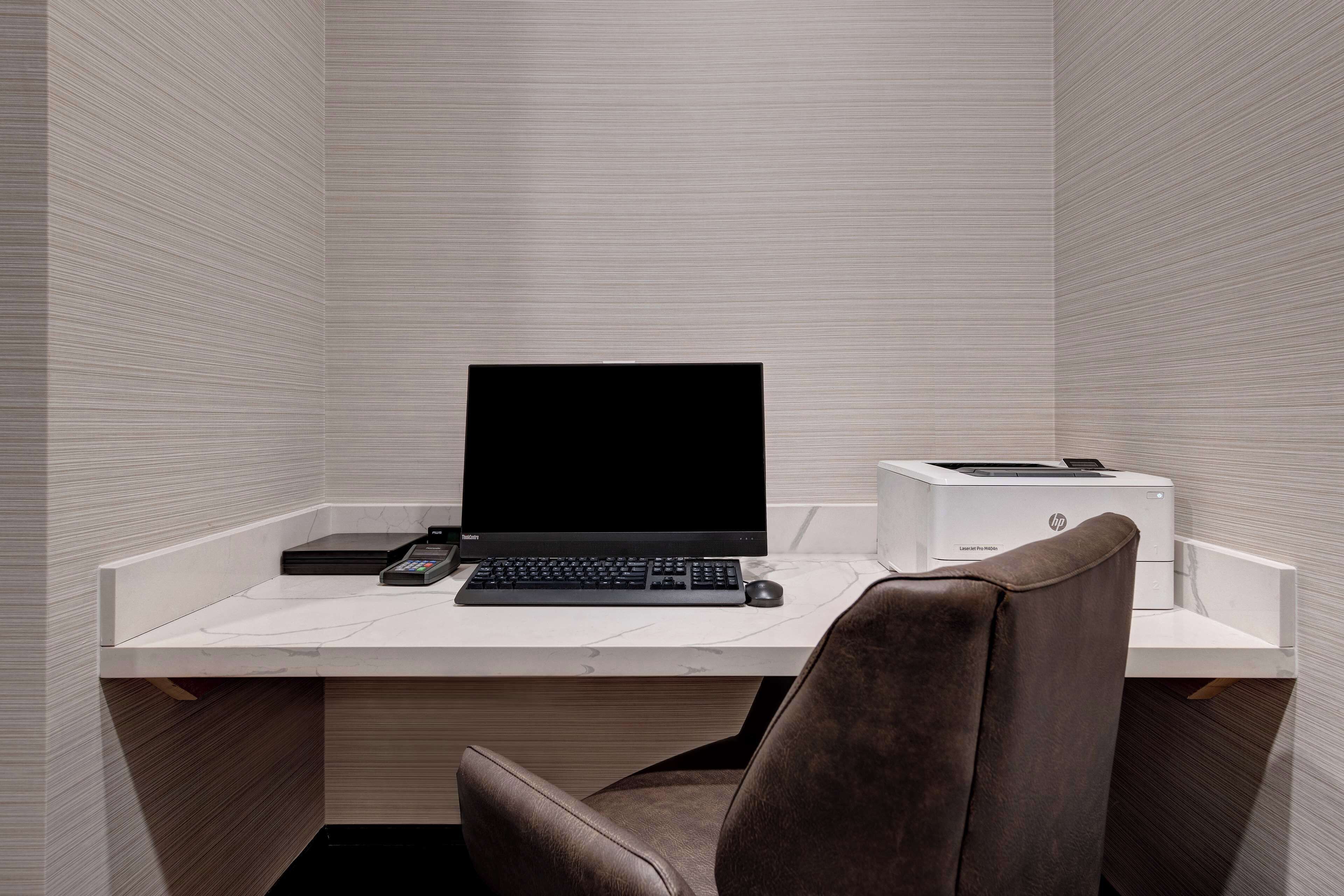 A modern office space with a white desk, a black monitor, a keyboard, a mouse, and an HP printer.