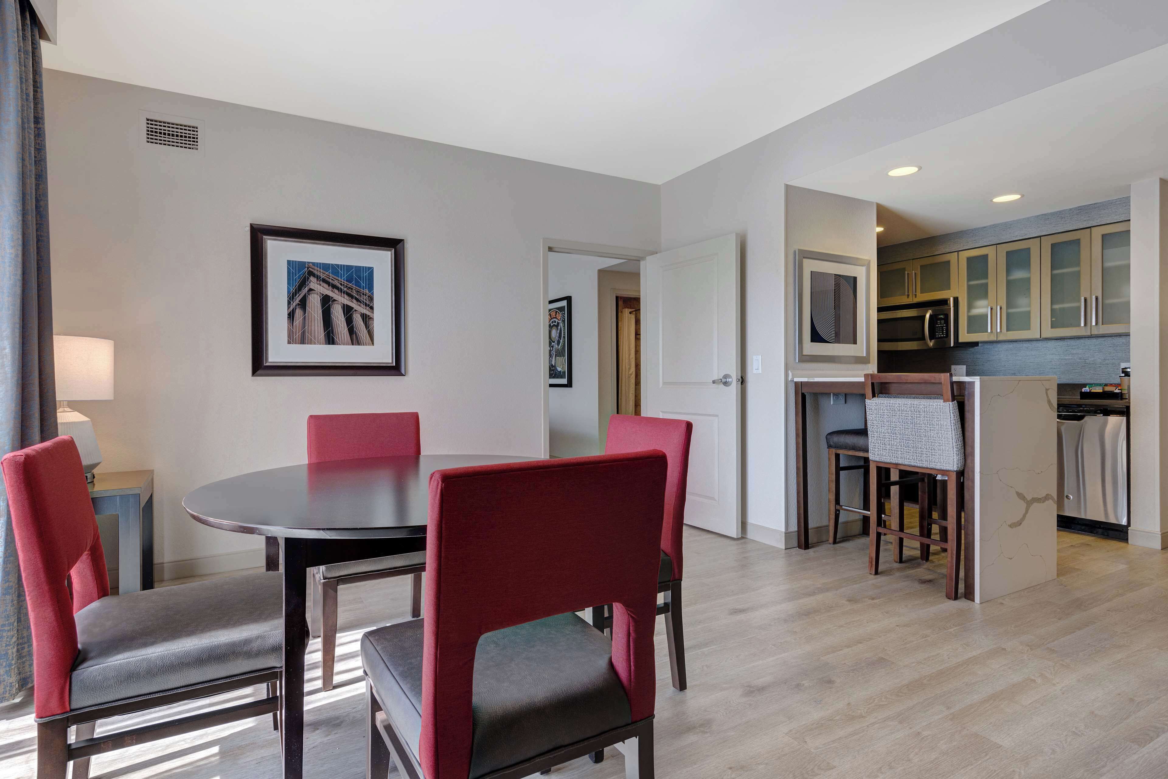 Quarto de hotel moderno com área de refeições, cozinha e corredor que dá para outro quarto.