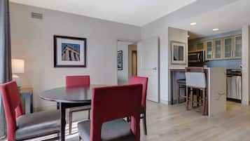 Quarto de hotel moderno com área de refeições, cozinha e corredor que dá para outro quarto.