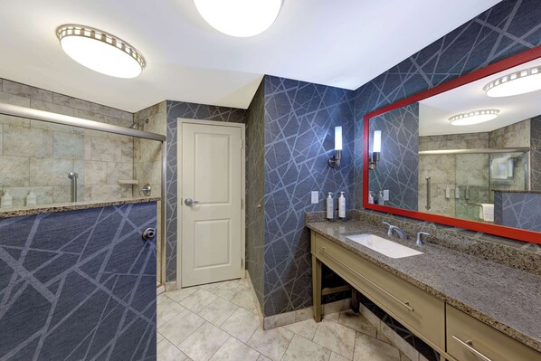 A modern bathroom with a large mirror, two sinks, and a shower area.