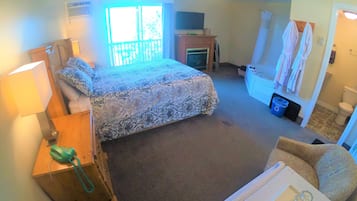 A bedroom with a bed, a desk with a lamp, a chair, a bathroom with a toilet and sink, and a ceiling fan.