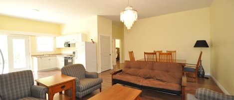 A living room with a sofa, chairs, a wooden coffee table, and a chandelier.