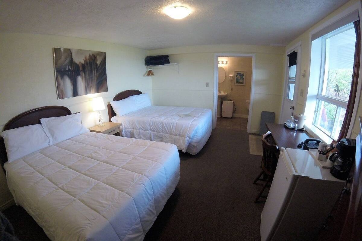 A hotel room with two beds, a desk, and a refrigerator.