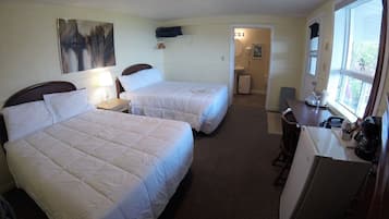 Une chambre d’hôtel avec deux lits, un bureau et un réfrigérateur.