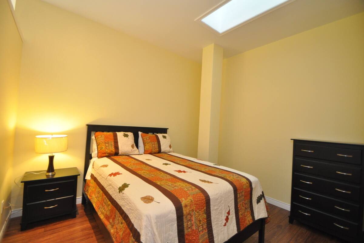 A bedroom with a bed, a nightstand, a dresser, and a skylight.