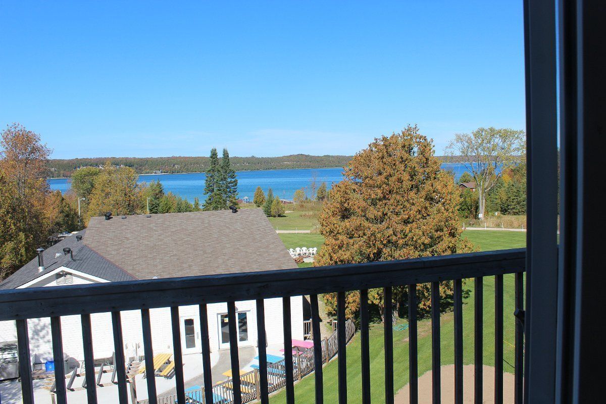 A view from a balcony overlooking a lake, with a white building and a grassy area in the foreground.