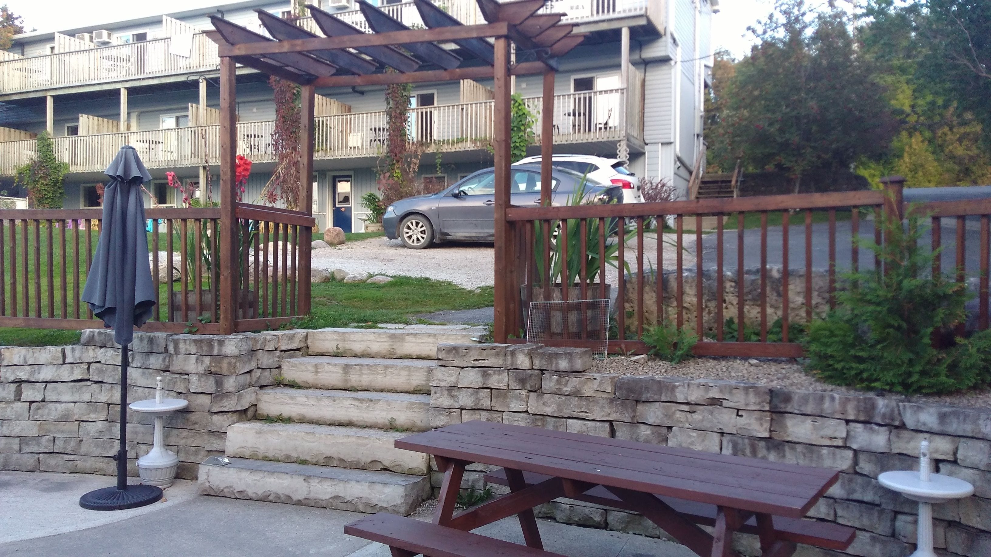 A patio area with a wooden pergola, stone steps, and a picnic table.