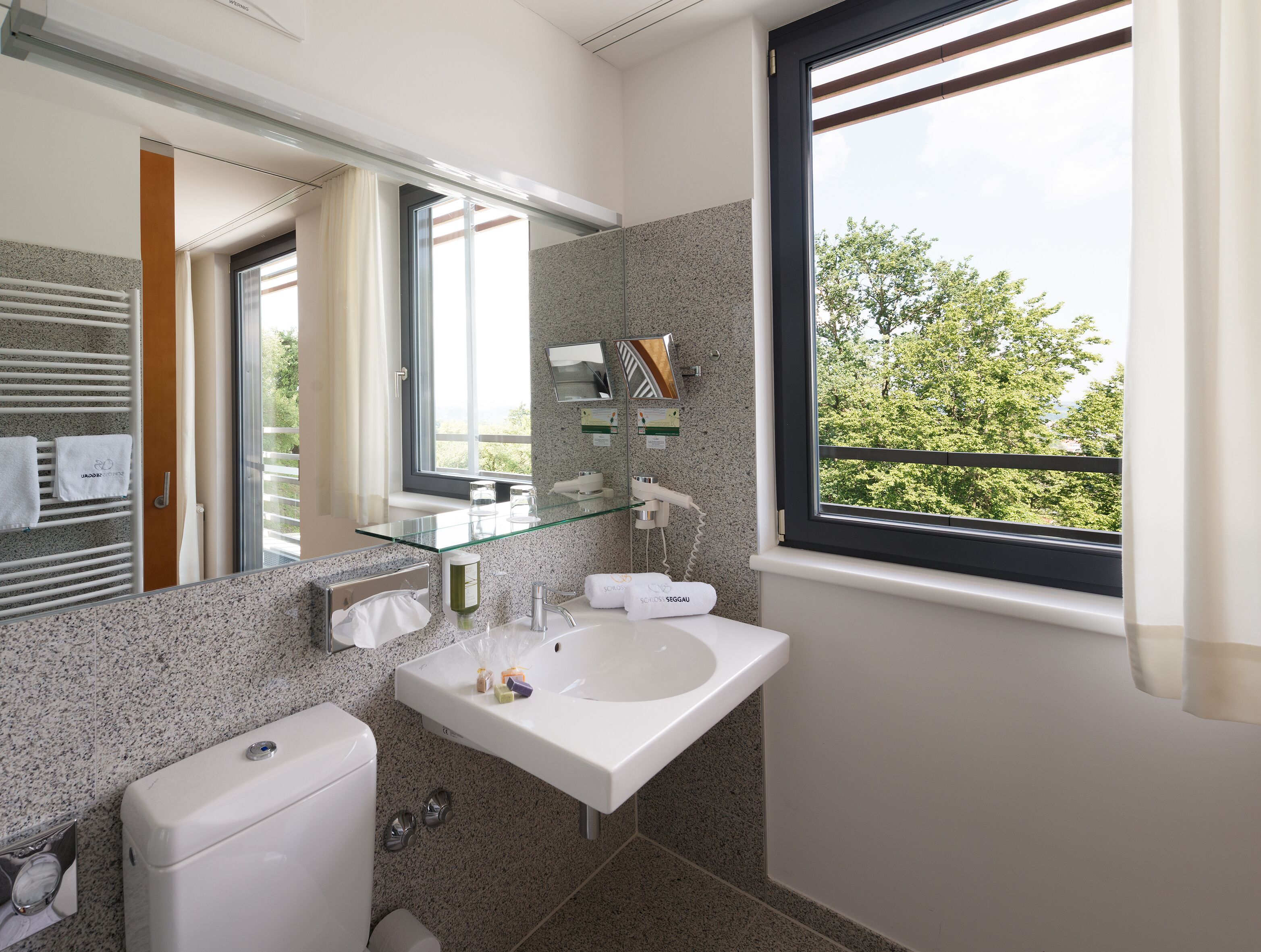 Un baño moderno con cabina de ducha de vidrio, un lavabo blanco y un espejo grande.