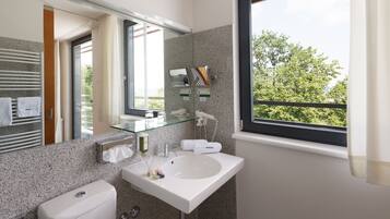 Un baño moderno con cabina de ducha de vidrio, un lavabo blanco y un espejo grande.
