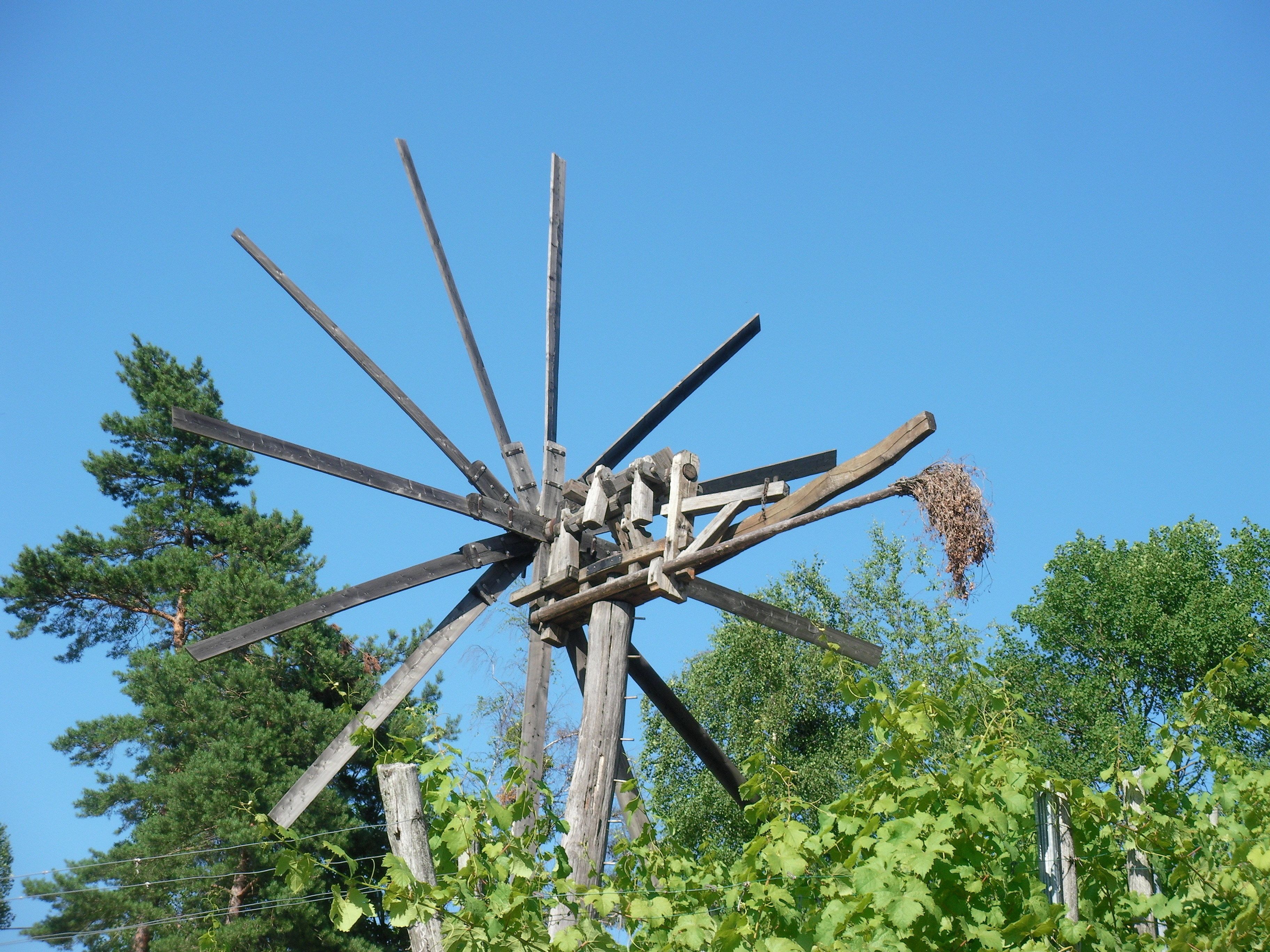 A windmill with a nest attached to one of its blades.