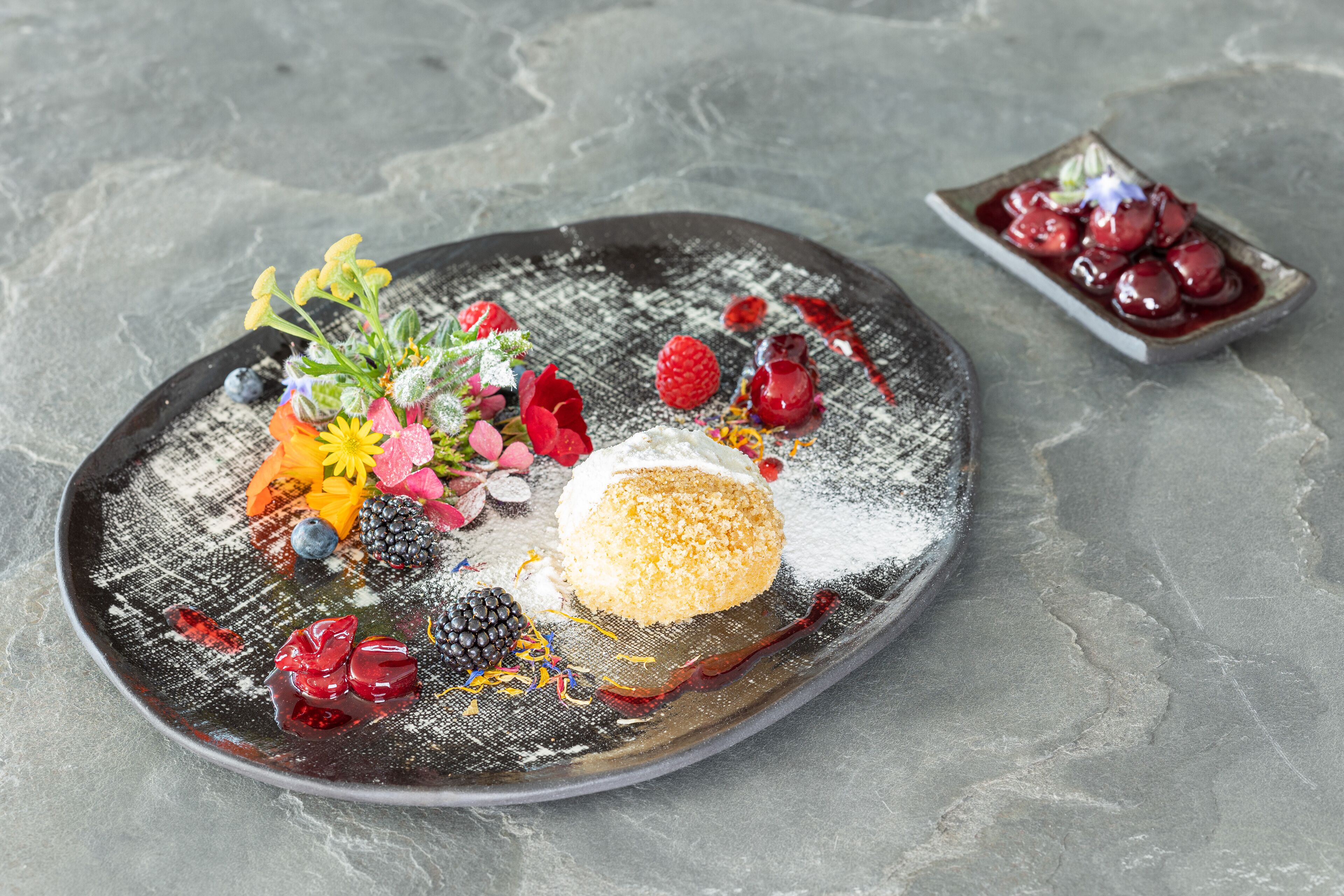 A dessert plate with various fruits and a small bowl of cherries.