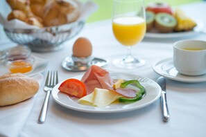 A breakfast setting with a plate of food, a glass of orange juice, and a bowl of pastries. - Schloss Seggau (Leibnitz)