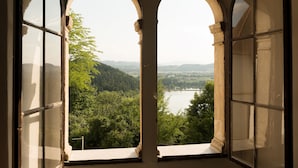 A room with two large arched windows offering a view of a lake and surrounding greenery. - Schloss Seggau (Leibnitz)