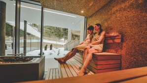 Un spa moderno con terraza de madera, paredes de vidrio y vistas a un paisaje nevado.
