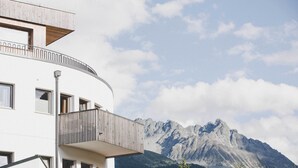 Un edificio moderno con varios balcones que dan a un paisaje montañoso.