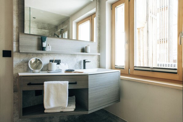 A modern bathroom with a large mirror, a sink, and a towel rack.