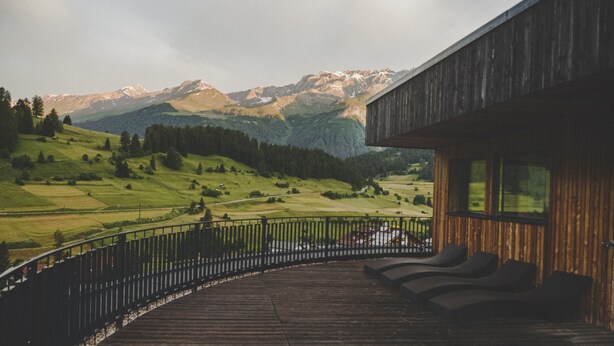 Una terraza de madera con sillones de descanso con vistas a un paisaje montañoso.