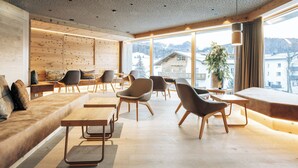 Un interior moderno con pared de madera, zona de estar y ventanas amplias que ofrecen vistas a edificios y montañas.