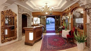 Eine prächtige Lobby mit verzierten Spiegeln, einer Kristallleuchter und einem roten Teppich zum Eingang.
