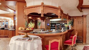 Eine Bar mit einer Holztresore, roten Sitzmöglichkeiten, einer Obstschale und einer Zeitung auf einem Tisch.