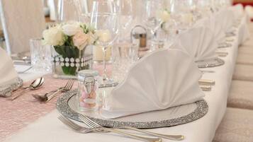 A table set with white napkins, silverware, and a decorative glass jar.
