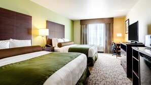 A hotel room with two beds, a desk, a TV, and a window with curtains. - Cobblestone Inn & Suites - Harper (Harper)