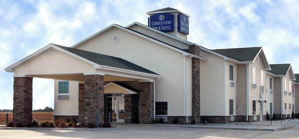 A Cobblestone Inn & Suites with a stone facade, a covered entrance, and a clear sky.