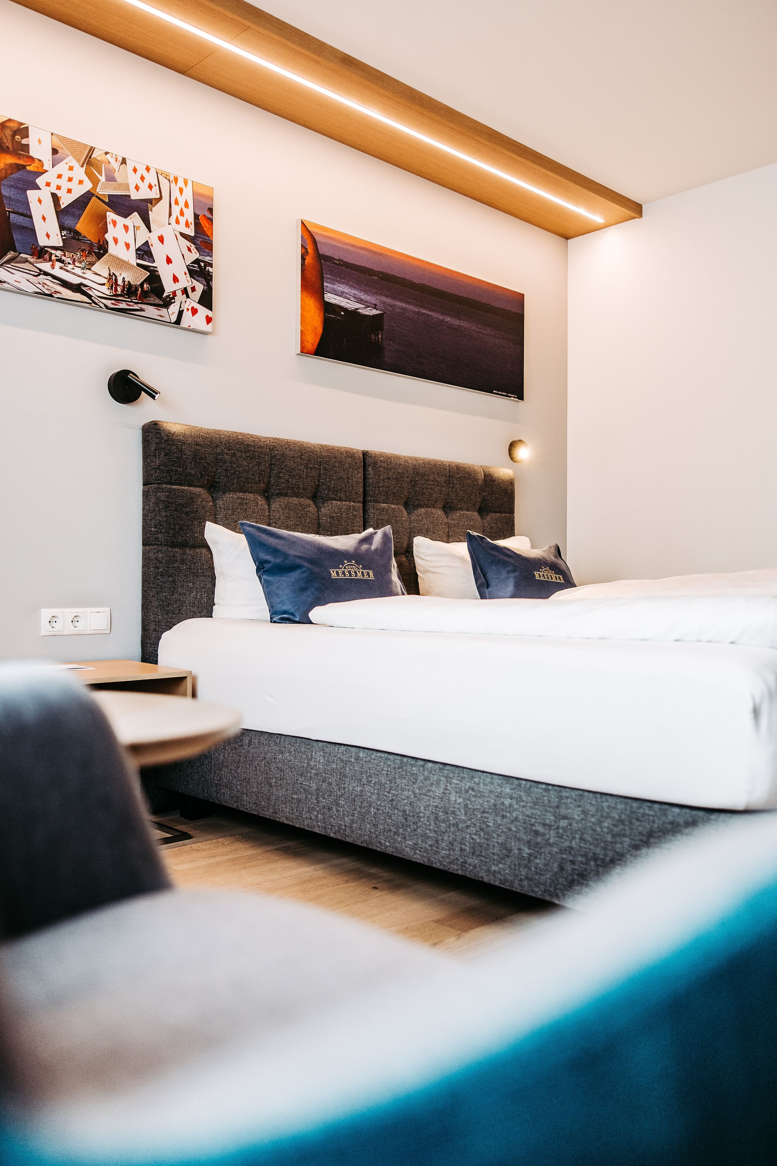 A modern hotel room with a large bed, a headboard, and a wall-mounted TV.