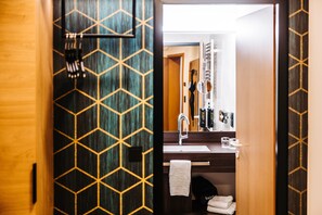 A bathroom with a geometric patterned door, a sink with a towel, and a mirror.