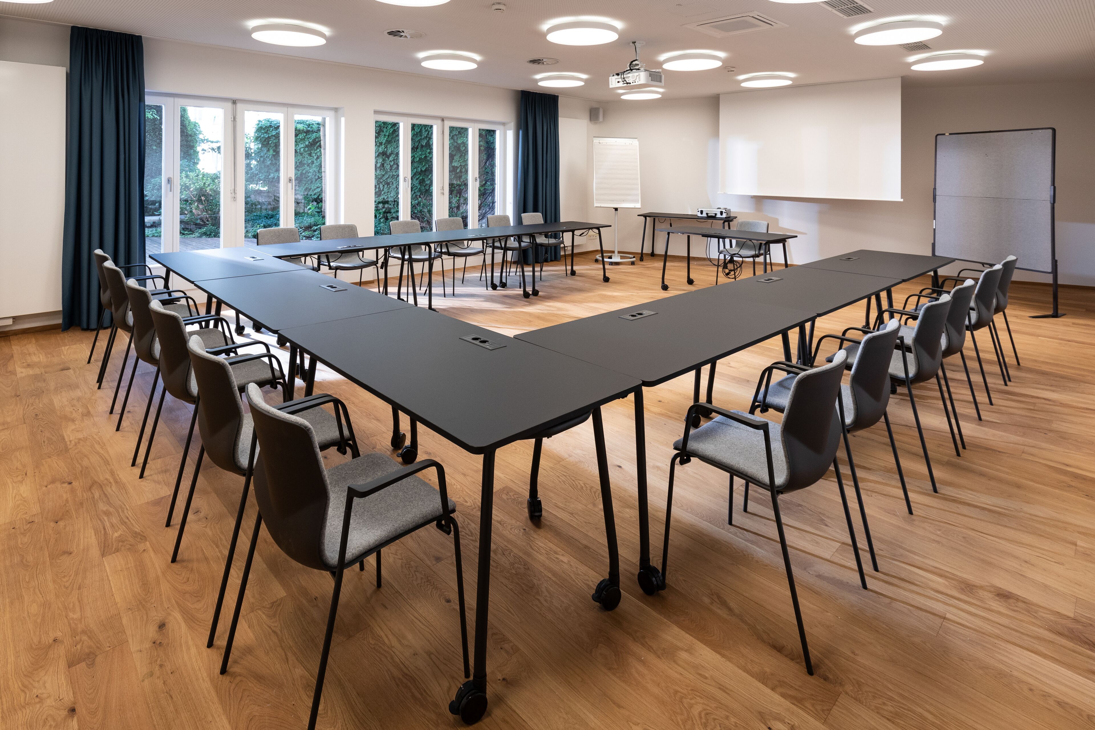 Een vergaderruimte met een lange tafel, stoelen, een beamer en een whiteboard.