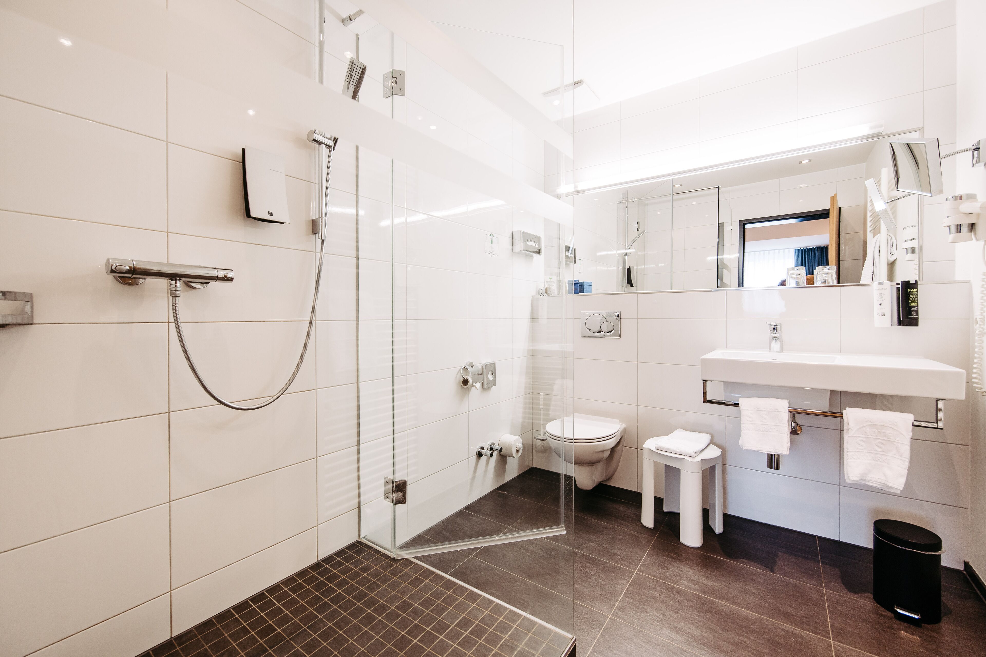 A modern bathroom with a glass-enclosed shower, a white sink, and a toilet.