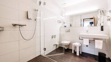 A modern bathroom with a glass-enclosed shower, a white sink, and a toilet.