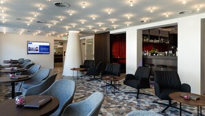A hotel lobby with seating areas, a bar, and a digital display. - Hotel Messmer (Bregenz)