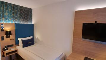 Une chambre d’hôtel comprenant un lit, une table de chevet, une lampe et un bureau avec une chaise.