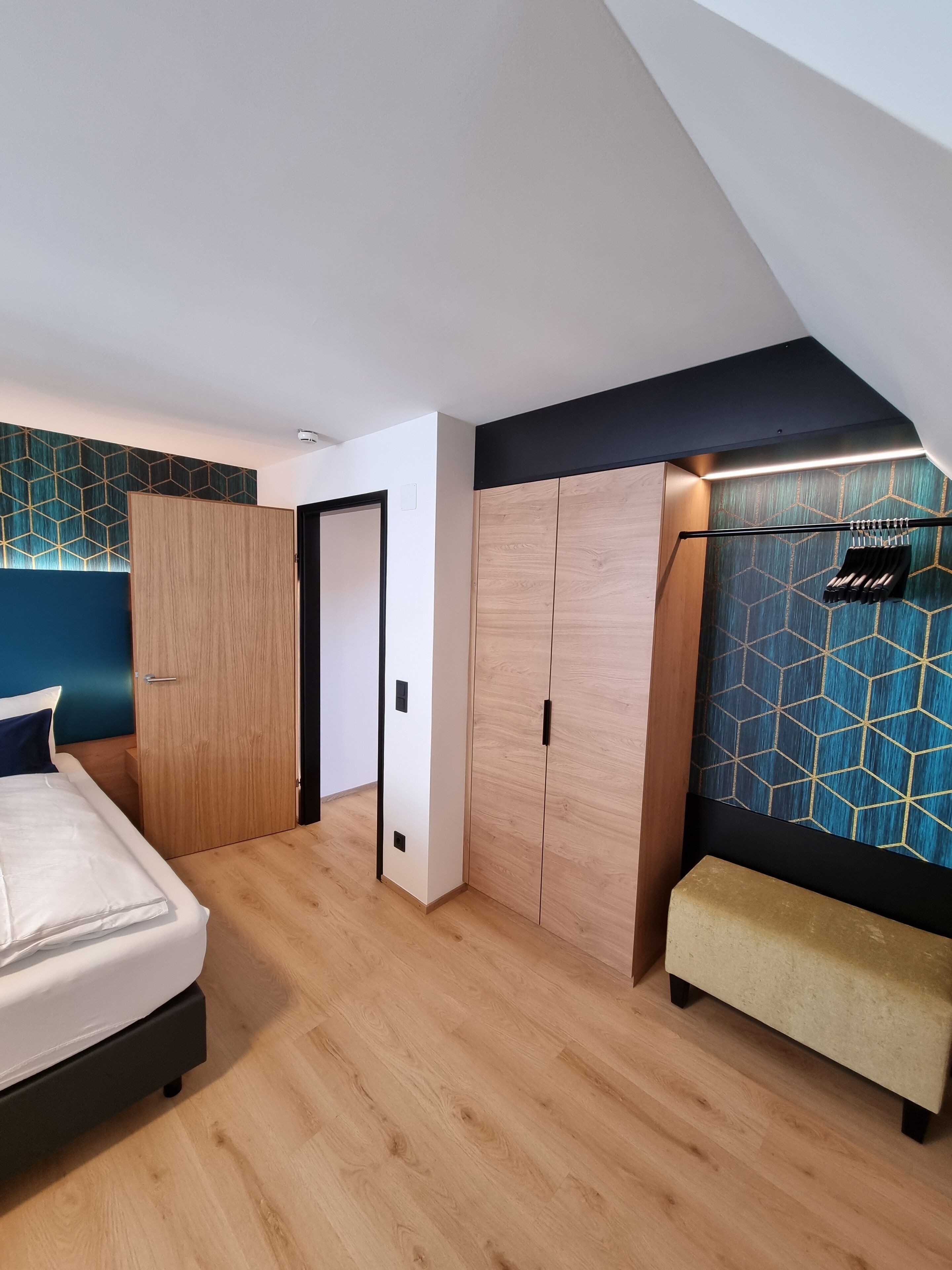A bedroom with a bed, wardrobe, and bench.