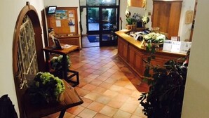 A hotel lobby with a reception desk, a wooden bench, and a tiled floor. - Hotel St. Hubertushof (Zell am See)