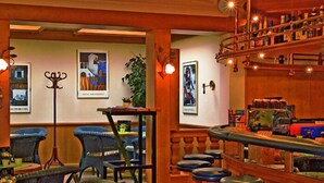 A bar area with wooden furniture, bar stools, and a variety of bottles on shelves. - Hotel St. Hubertushof (Zell am See)