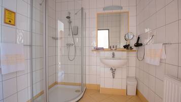 A modern bathroom with a glass-enclosed shower, a sink, and a mirror.