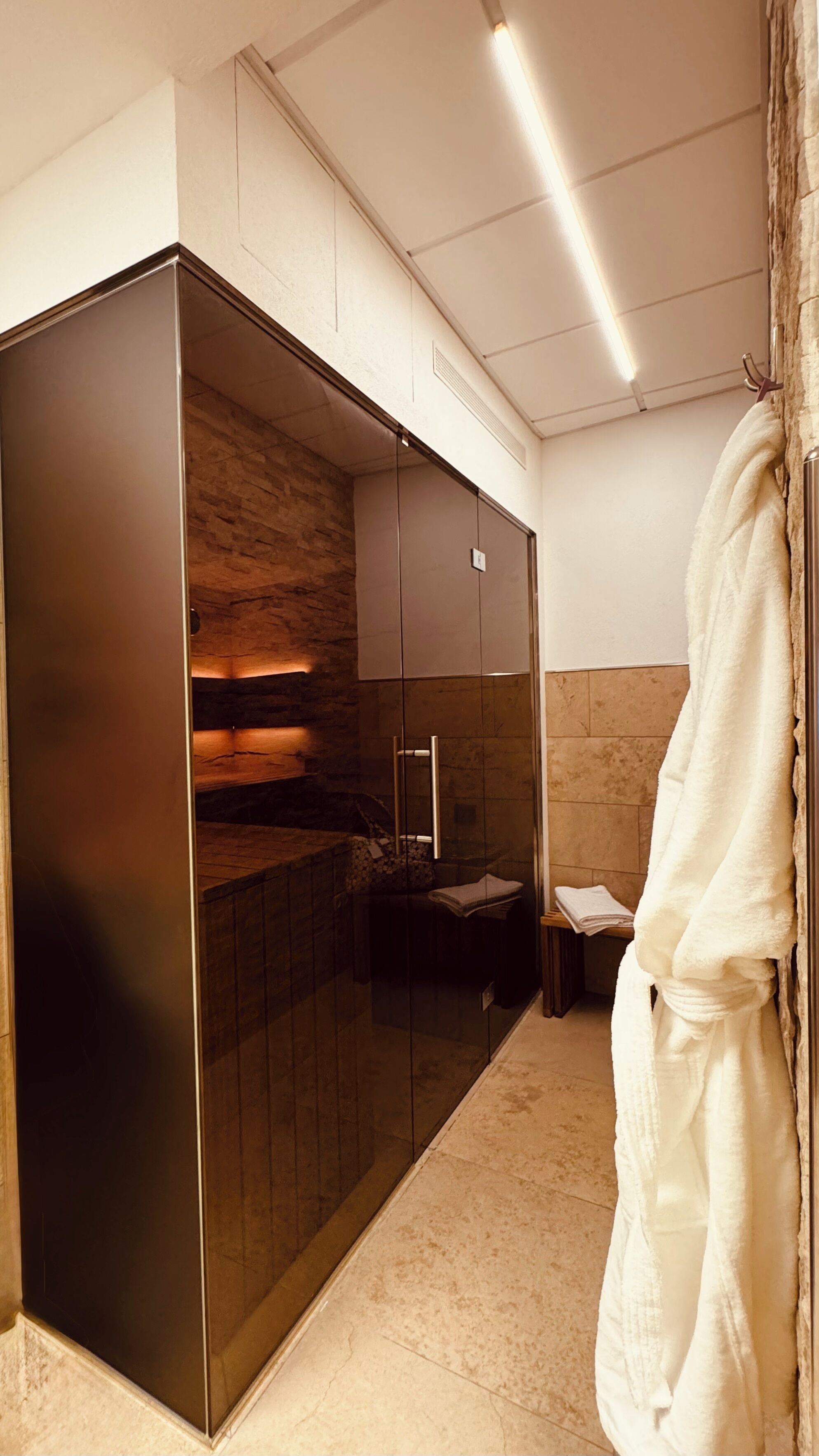 Ein modernes Badezimmer mit einer gläsernen Duschkabine, einer Holzwand und einem Handtuchhalter.