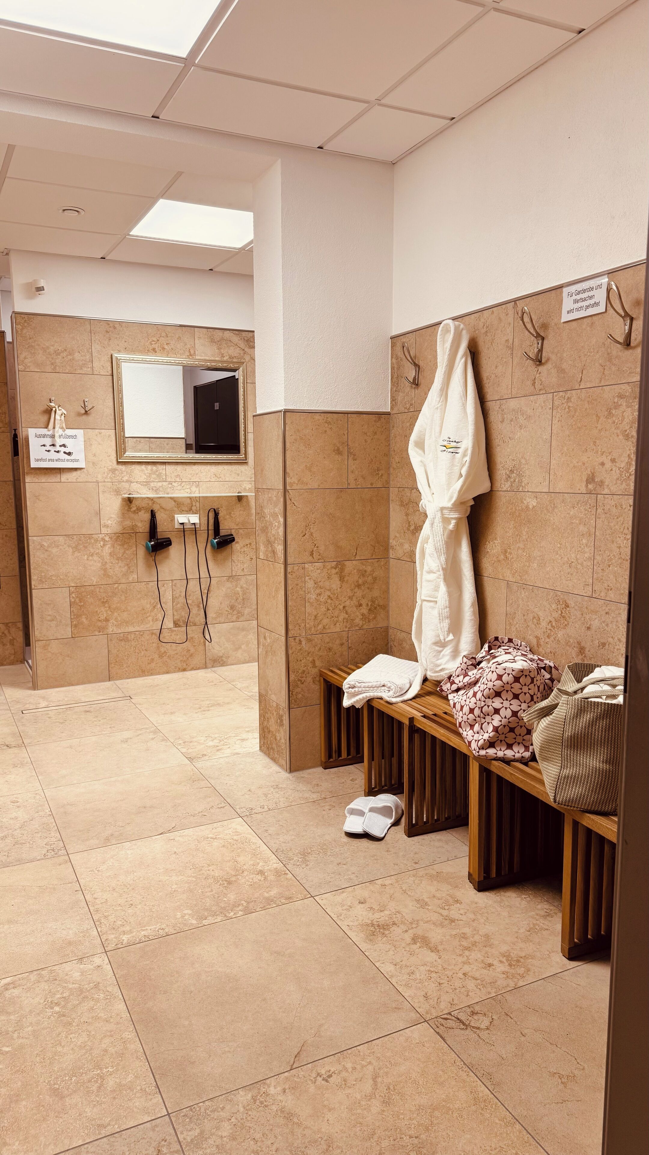 Baño público con banco, toallero y espejo.