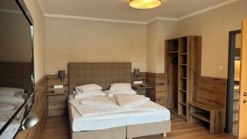 Una habitación de hotel con una cama grande, mesitas de noche, un armario de madera y un espejo.