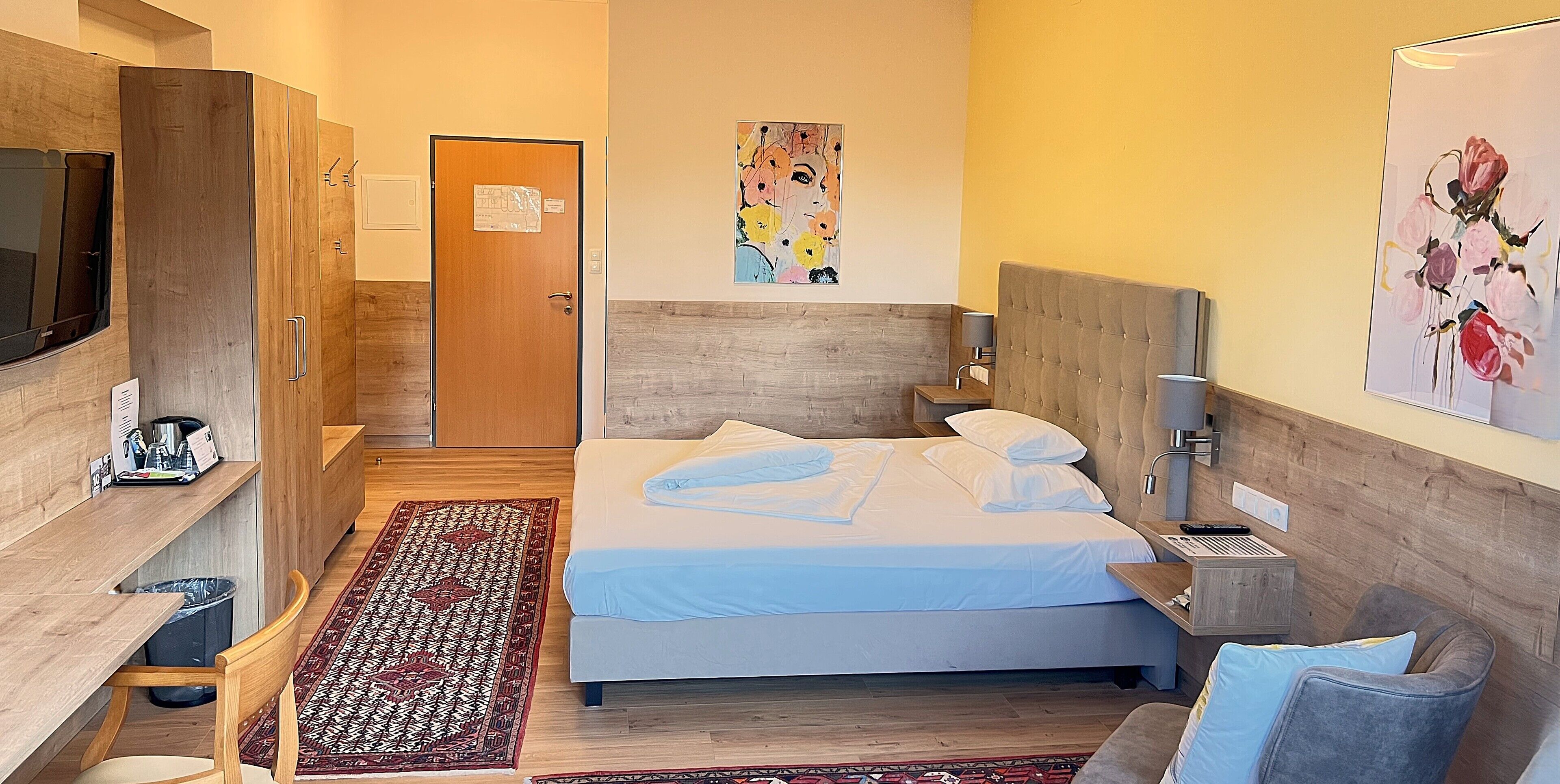 A hotel room with a bed, a TV, a desk, and a chair.