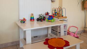 A child's play area with a white table, toys, and a radiator.