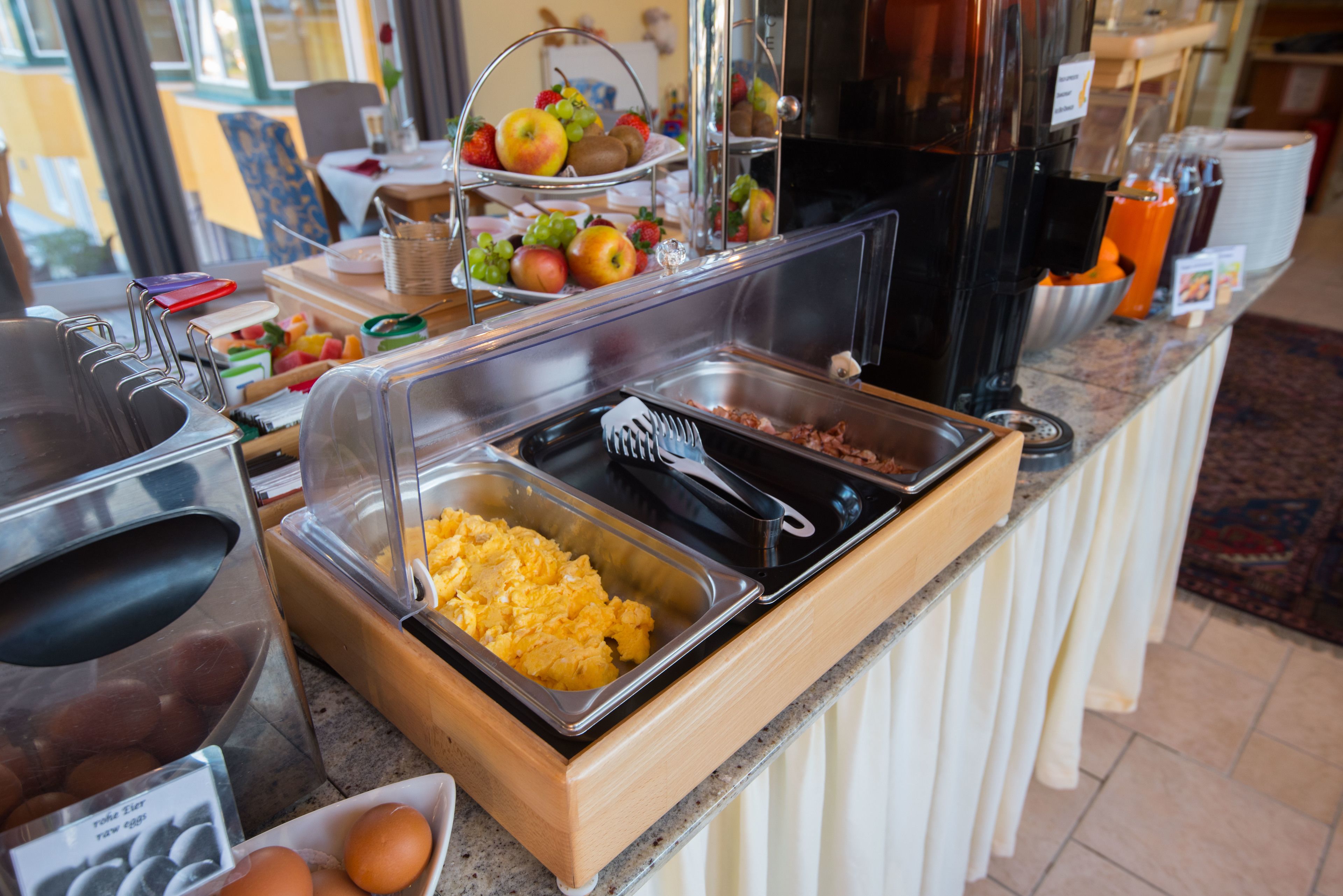 Un buffet con diversi cibi tra cui frutta, uova e uova strapazzate.