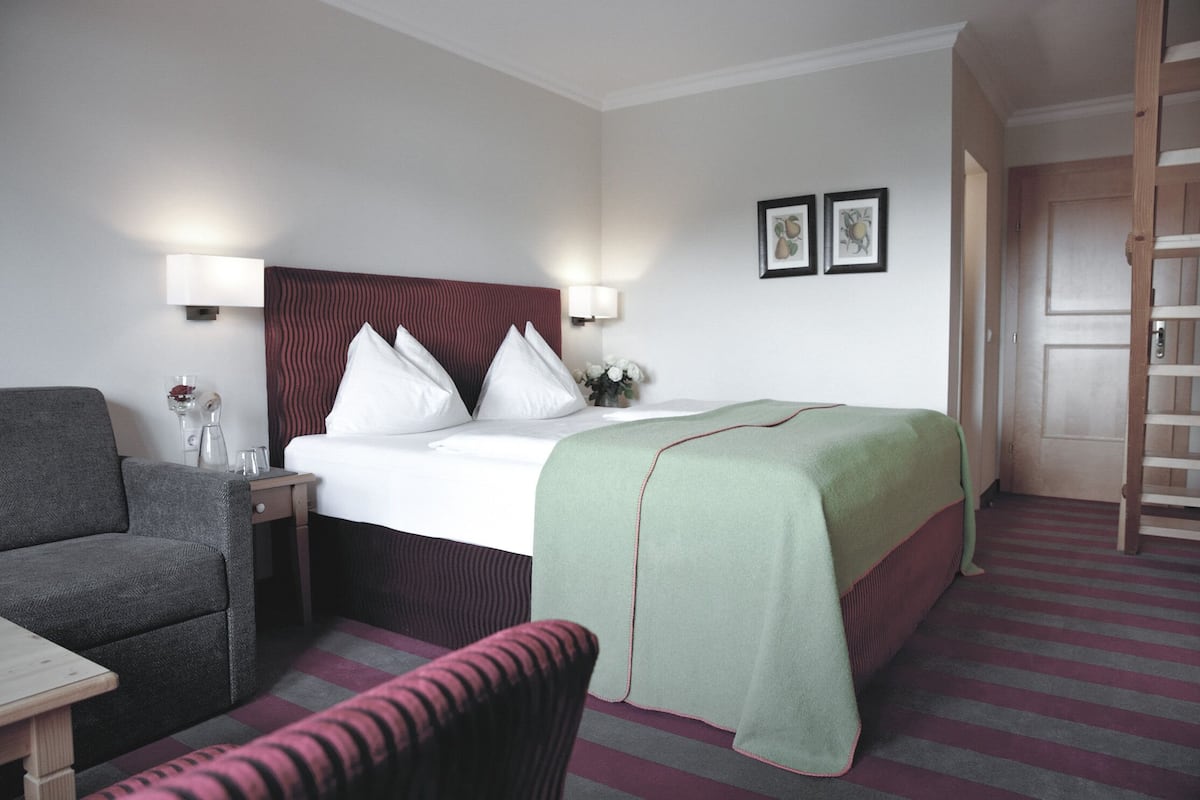 A hotel room with a bed, a chair, a desk, and a nightstand.