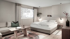 Una camera d'albergo moderna con un letto, un divano, una scrivania e una grande finestra.