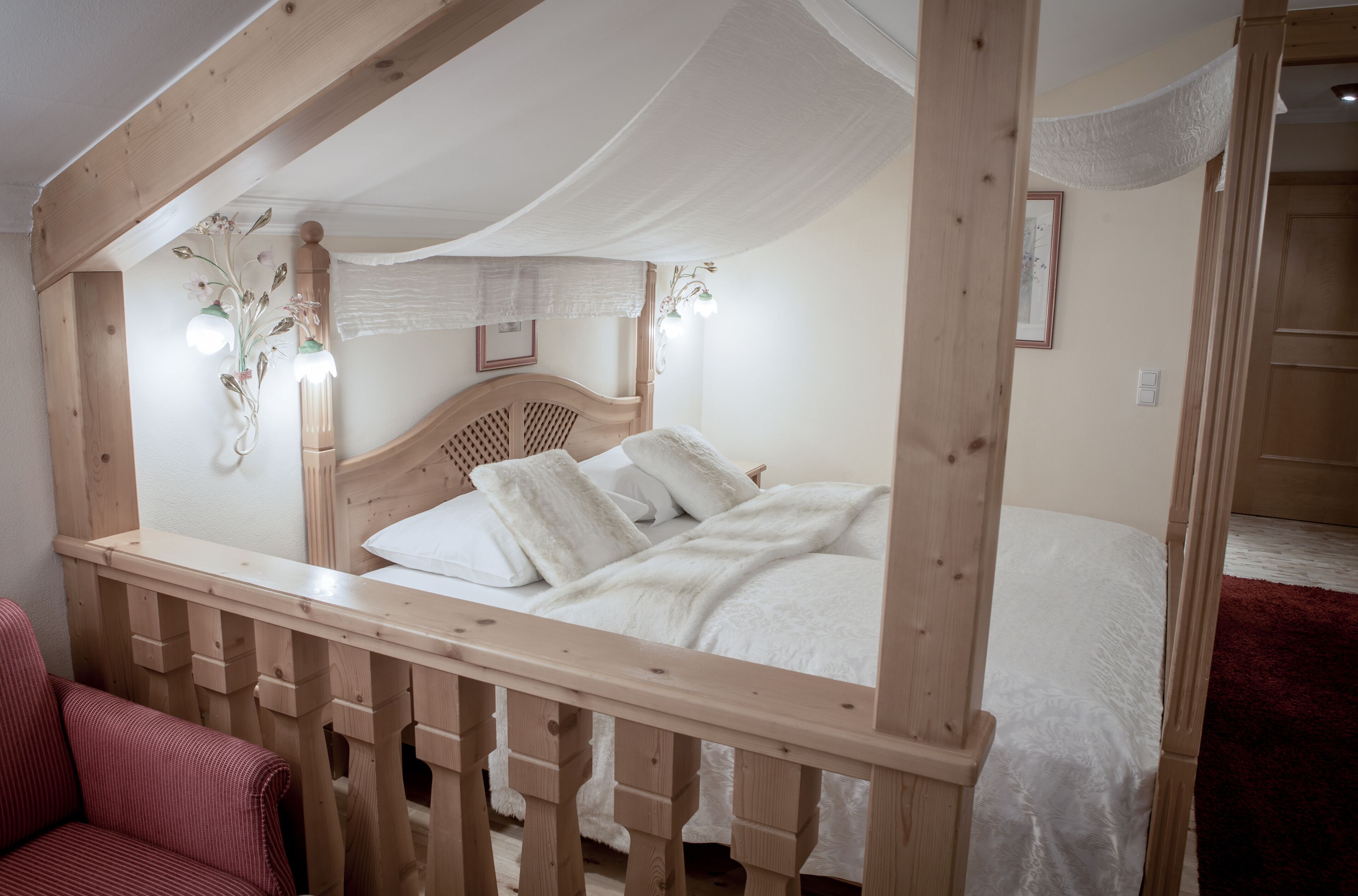 A wooden four-poster bed with white bedding, a wooden headboard, and a canopy.