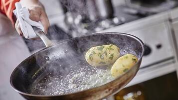 Una persona cucina patate in una padella sul fornello.