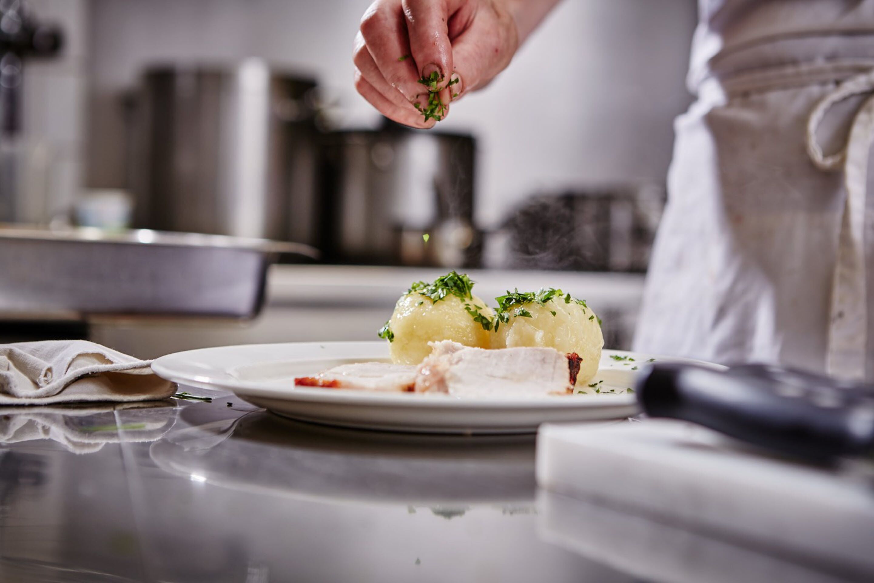 Un chef adornando un plato con hierbas.
