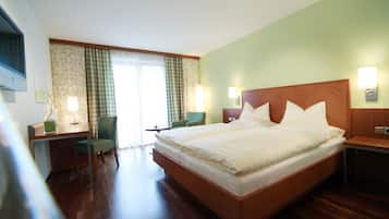 Una habitación de hotel con una cama grande, un escritorio, una silla y una ventana con cortinas.